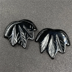 Macro detail of hand-carved black obsidian maple leaf pendants with intricate vein patterns