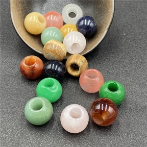 Close-up of assorted natural stone large hole beads spilling from a black bowl for DIY jewelry
