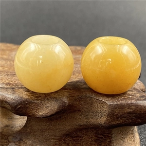 Macro view of two 20mm round yellow agate beads with polished finish on a wooden stand