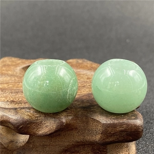 Macro view of two 20mm green aventurine loose beads with large holes on wood base
