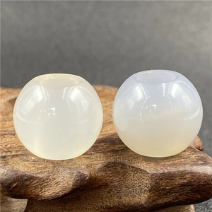 Macro shot of two polished semi-translucent agate beads on a vintage wooden base for DIY jewelry