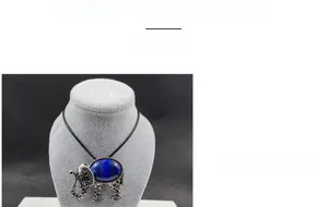 Vue macro d'un pendentif éléphant en argent rétro avec cristal bleu sur un buste gris