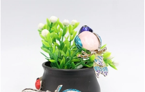 Detailed close-up of a magpie bird brooch with pink gemstone and blue enamel wings