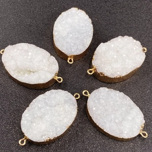 Macro detail of five white druzy crystal pendants with gold edges and double connectors