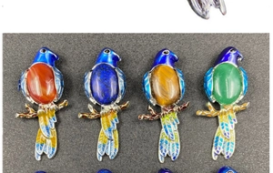Detailed view of colorful bird brooches with enamel finish and gemstone inlays