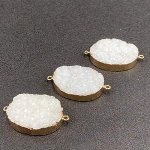 Macro shot of three oval druzy quartz connectors with gold plated edges and double loops