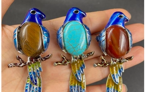 Macro view of bird brooches featuring enamel wings and natural gemstone bellies on branches
