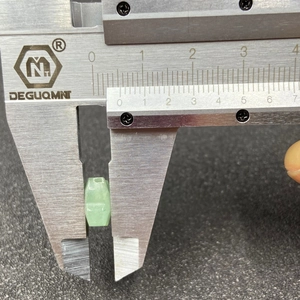 Macro view of a light green aventurine clover bead measured by a digital caliper