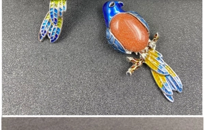 Macro shot of colorful enamel magpie brooch with a sparkling orange goldstone inlay