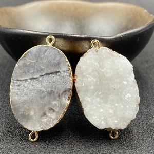 Detailed view of dual-loop geode pendants with gold edging and natural crystal texture