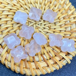 Detailed macro view of pink crystal clover beads with geometric facets on woven mat