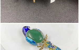 Detailed view of parrot brooch with green oval stone and multicolored enamel wings