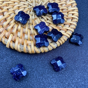 Macro shot of blue sandstone four-leaf clover beads with sparkling metallic luster