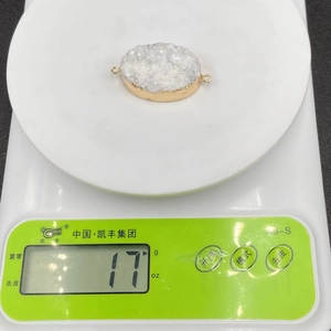 Detailed view of 17g white druzy quartz pendant with gold electroplated edges on scale