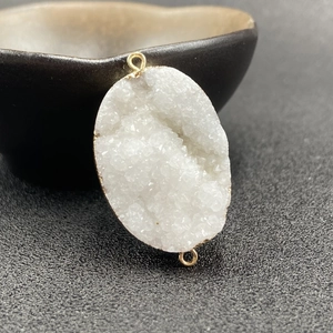 Macro shot of white druzy quartz pendant with gold electroplated edges and double rings