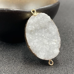 Macro view of white quartz druzy geode pendant with electroplated gold edge connectors