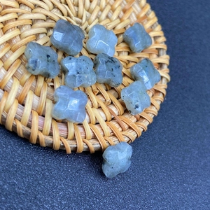 Macro detail of 10 grey moonstone four-leaf clover beads on a rustic woven coaster