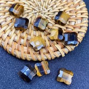 Macro detail of hand-carved tiger eye four-leaf clover loose beads on woven mat