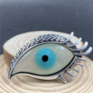 Vue détaillée d'une broche œil avec iris bleu sur un support en bois naturel
