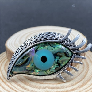 Vue macro d'une broche œil de protection avec nacre d'abalone et détails de cils argentés