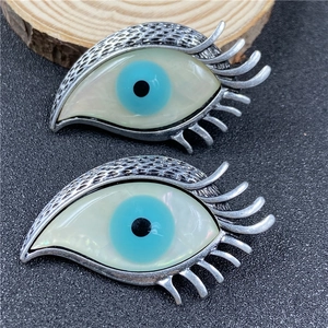 Détail de broches œil vintage en argent avec incrustation de coquillage arc-en-ciel