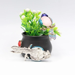 Enameled magpie bird brooch with pink gemstone showing front and back views