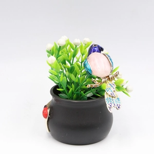 Vibrant magpie bird brooch with pink gemstone and blue enamel detail on a small plant