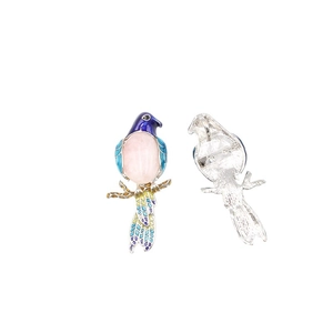 Magpie bird brooch with colorful enamel finish and gemstone inlay on white background