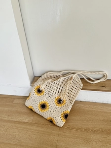 Macro detail of sunflower crochet tote bag with intricate cotton knit textures and fringe