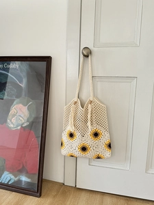 Detail of hand-woven sunflower tote bag with cotton tassels hanging on a door handle