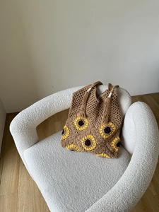 Detail of hand-woven crochet tote bag featuring yellow sunflower and boho tassel accents