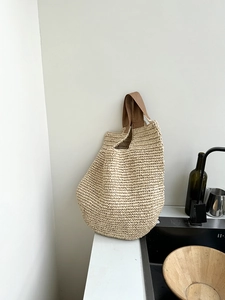 Close-up of hand-woven straw shoulder bag with durable brown cotton handles for summer travel
