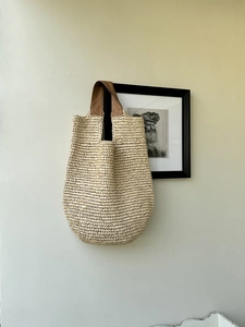 Detail view of woven straw shoulder bag with durable brown leather handle and fine texture