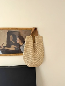 Detailed texture of hand-woven beige straw tote bag with brown fabric handles