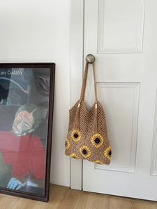 Detail of sunflower crochet tote bag with fringe accents hanging on a classic door handle