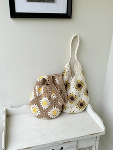Detailed shot of two handmade crochet tote bags with 3D daisy flowers on a wooden table