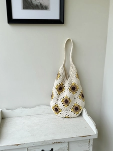Detailed macro view of handmade crochet sunflower shoulder bag on vintage cabinet