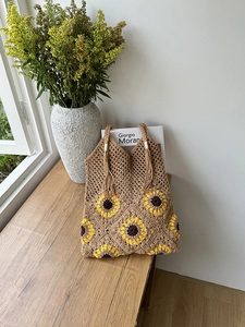 Detail of sunflower crochet tote bag with fringe tassel on a wooden surface