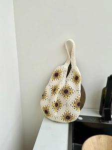 Detail of hand-crocheted tote bag featuring yellow sunflower patterns on creamy fabric