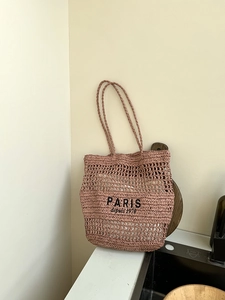Nahaufnahme der Paris-Stickerei auf einer altrosa Strohtasche mit Mesh-Details
