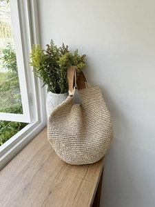 Detail of hand-woven straw shoulder bag texture with premium brown leather strap