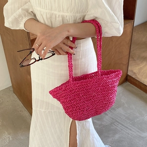 Handwoven straw shoulder bag in vibrant magenta with textured V-weave for summer beach vacations