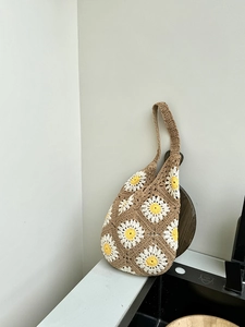 Detail of handmade crochet daisy flower pattern on brown woven summer tote bag