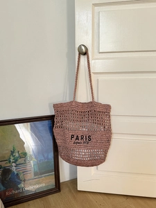 Detail einer hohlen Strohtasche mit Paris-Stickerei an einem Türgriff aufgehängt