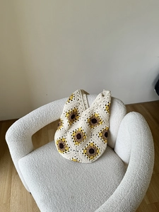 Detail of handcrafted crochet tote bag with retro sunflower patchwork on white boucle fabric