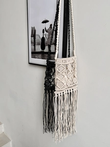 Detail of bohemian hand-woven crossbody bags with tassels in black and beige colors