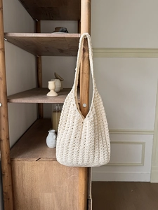 Detailed view of cream woven hobo bag showing handmade crochet texture and wide shoulder strap