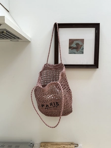 Detail der hohlen Strohtasche mit PARIS-Stickerei und zwei gewebten Griffen für den Strand