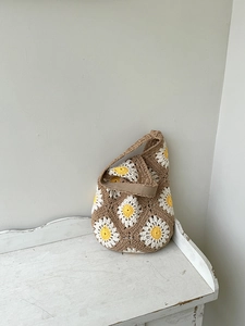 Close-up of handmade crochet shoulder bag with white and yellow daisy flower patterns