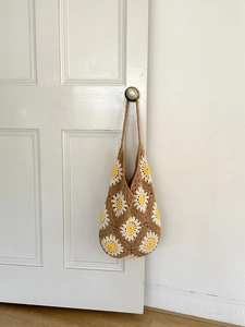 Detail of a handmade brown crochet shoulder bag with white daisy flower patterns
